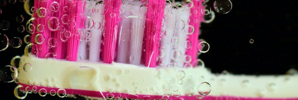 Pink and white toothbrush surrounded by bubbles