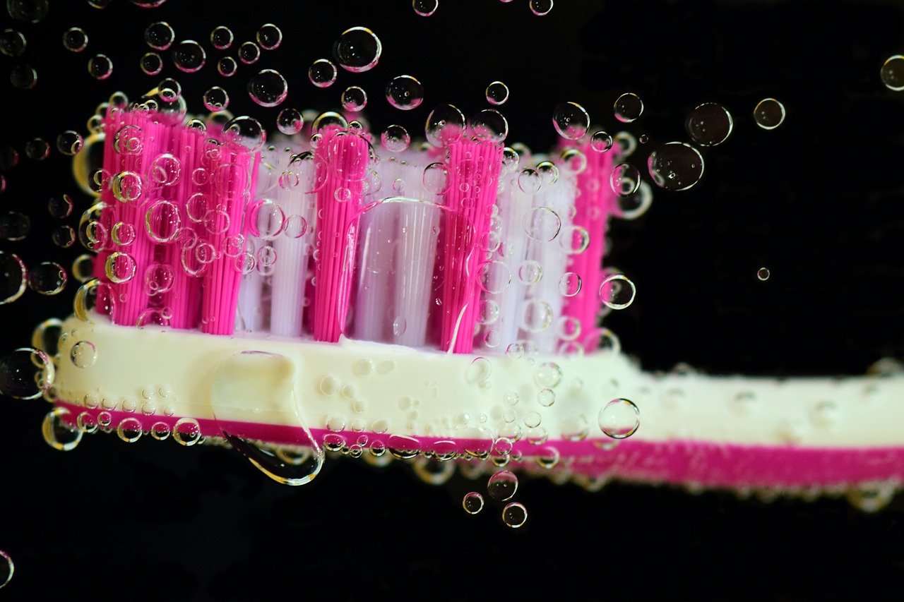 Pink and white toothbrush surrounded by bubbles