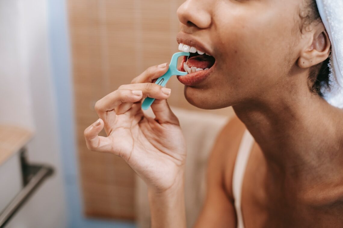 Person cleaning teeth with dental floss