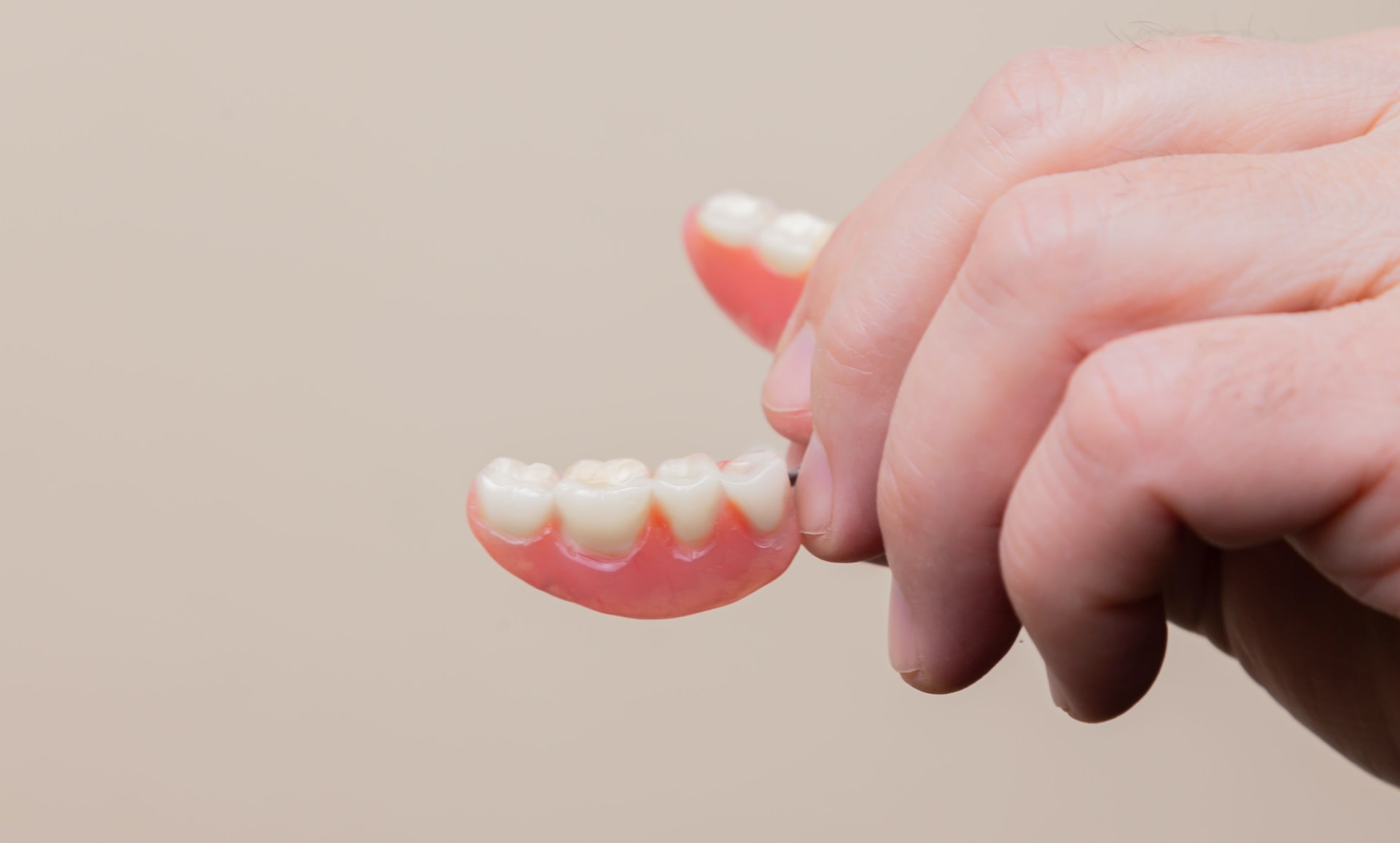Person holding a set of dentures.