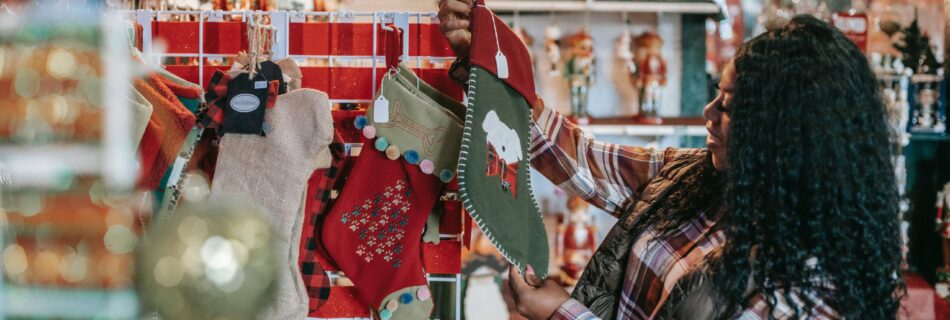 A Black woman in a plaid shirt holding up a stocking and looking at it