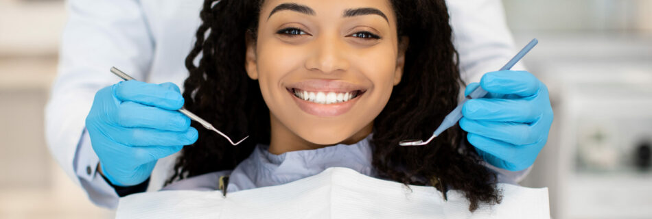 Portrait Of Happy Young Black Woman Having Check Up At Dental Clinic, Closeup Shot Of Millennial African American Female Patient Getting Teeth Treatment With Dentist In Modern Stomatologic Cabinet