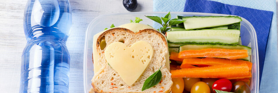 Healthy lunch box with sandwich and fresh vegetables, bottle of water.