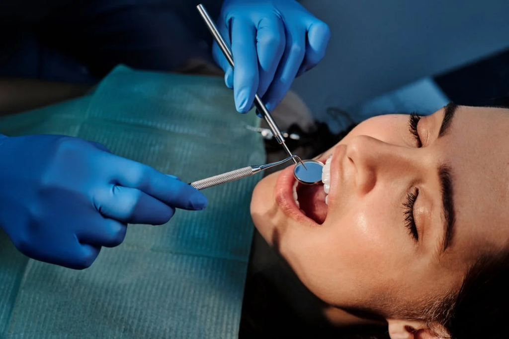 Person laying in a procedure chair being examined by a dentist.