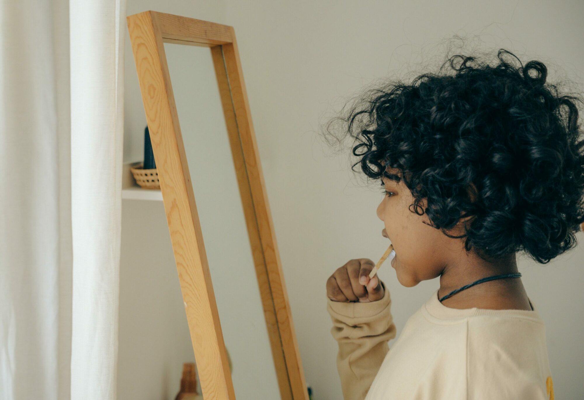 Child brushing teeth in front of a mirror.
