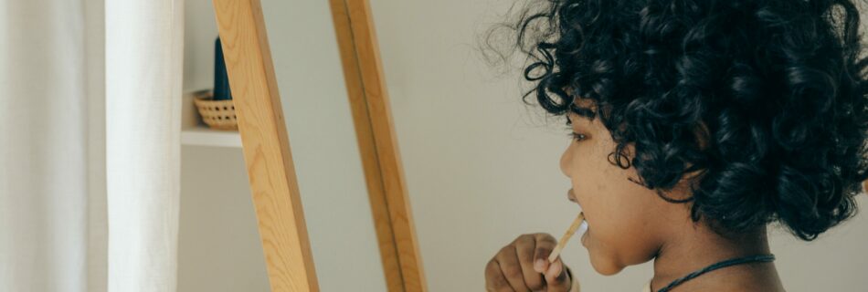 Child brushing teeth in front of a mirror.