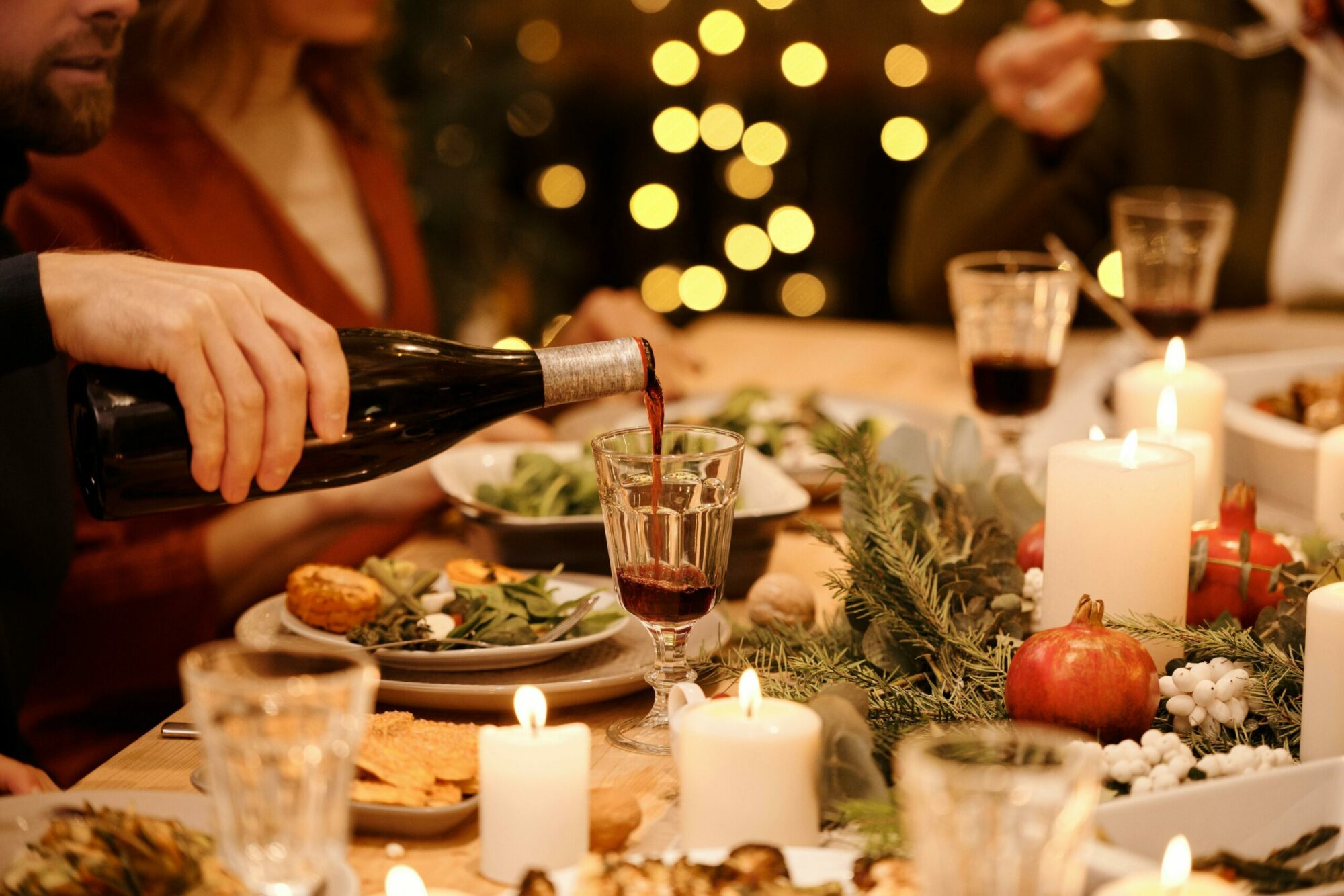 A candlelit thanksgiving table with a glass of wine being poured.