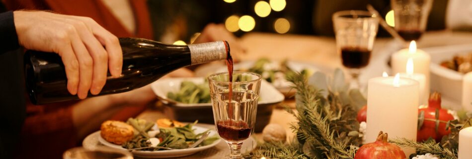 A candlelit thanksgiving table with a glass of wine being poured.