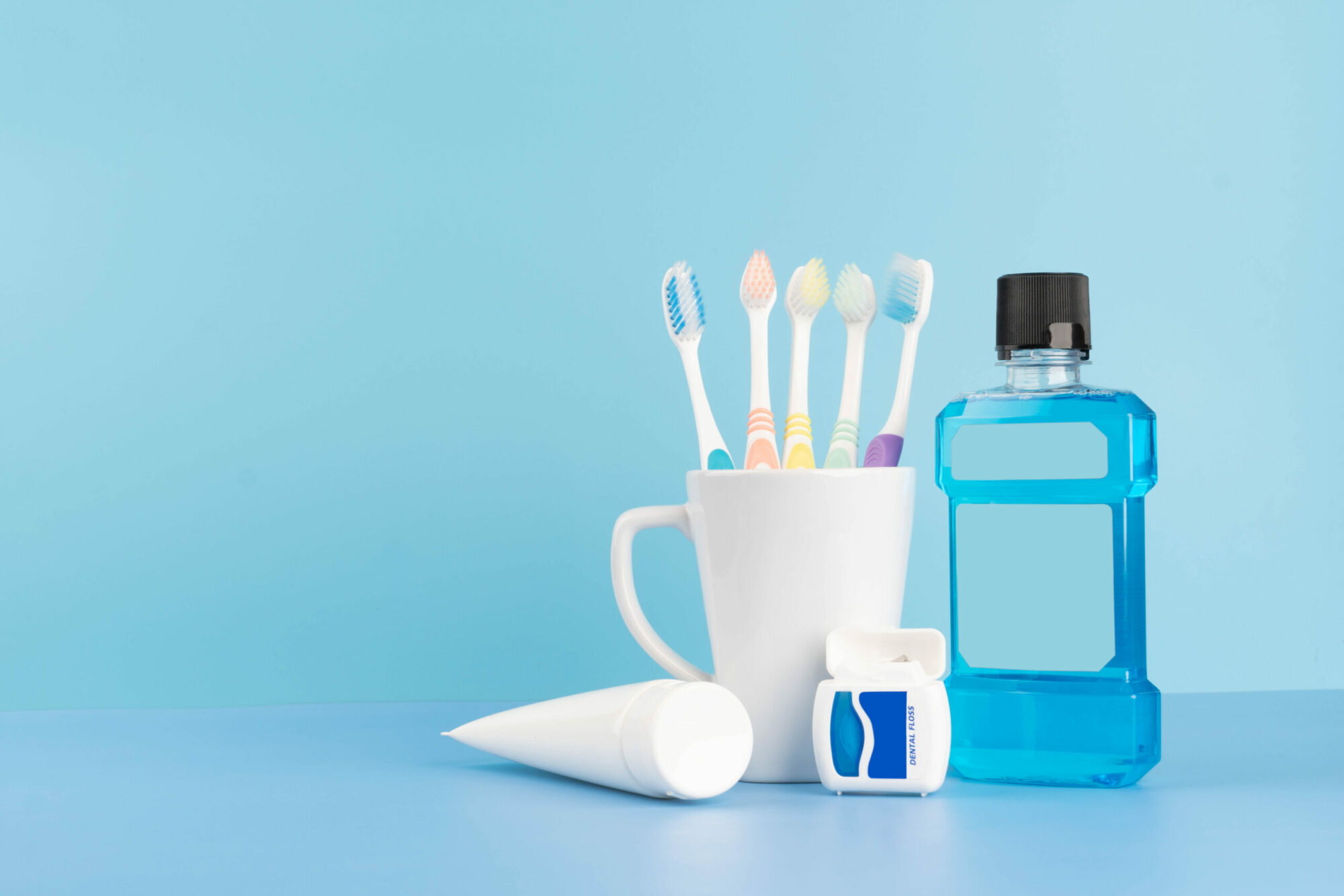 Oral care products set for healthy teeth and gums. Toothbrushes in glass with toothpaste, mouthwash and dental