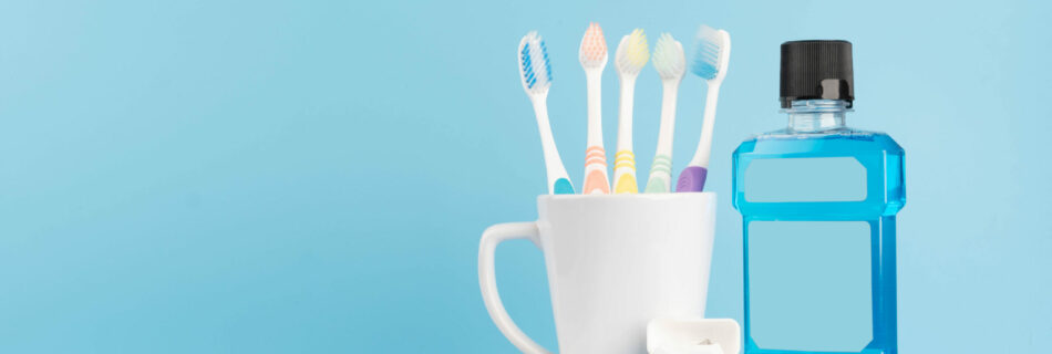 Oral care products set for healthy teeth and gums. Toothbrushes in glass with toothpaste, mouthwash and dental