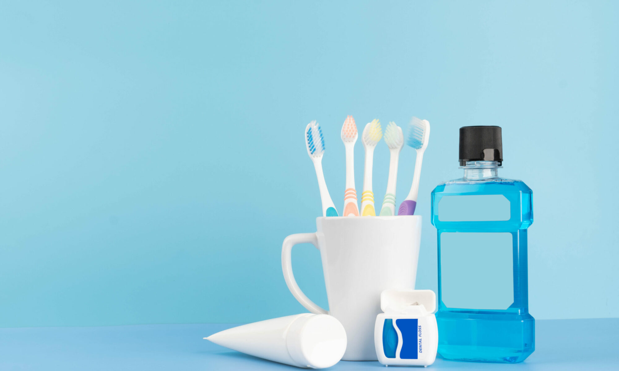 Oral care products set for healthy teeth and gums. Toothbrushes in glass with toothpaste, mouthwash and dental
