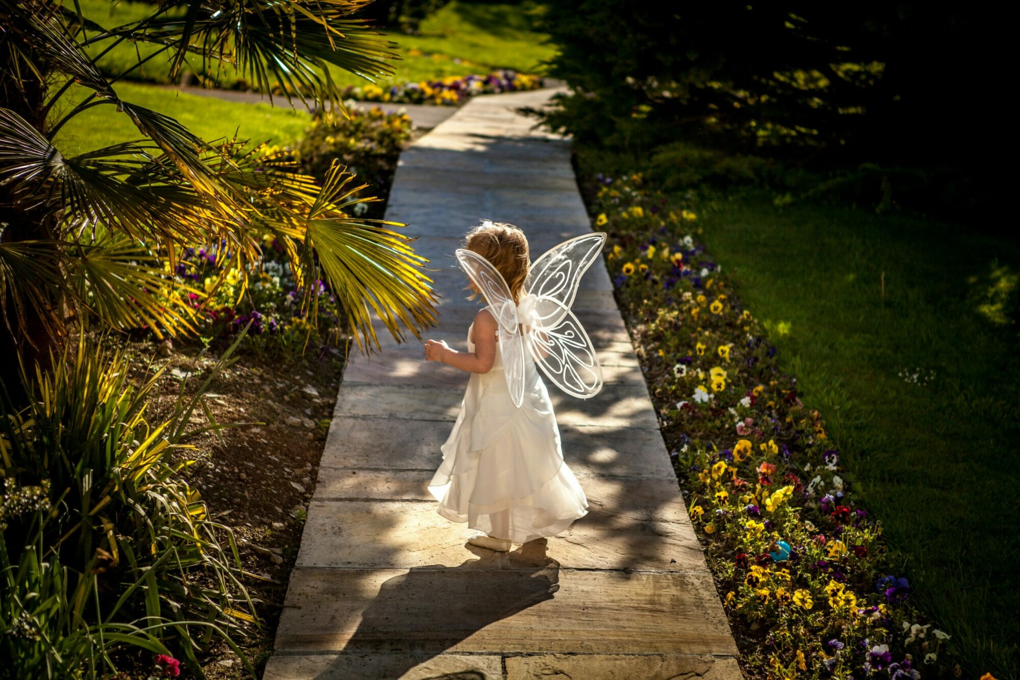 girl wearing angel costume standing on wooden pathway