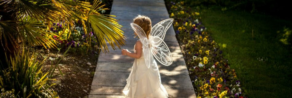 girl wearing angel costume standing on wooden pathway