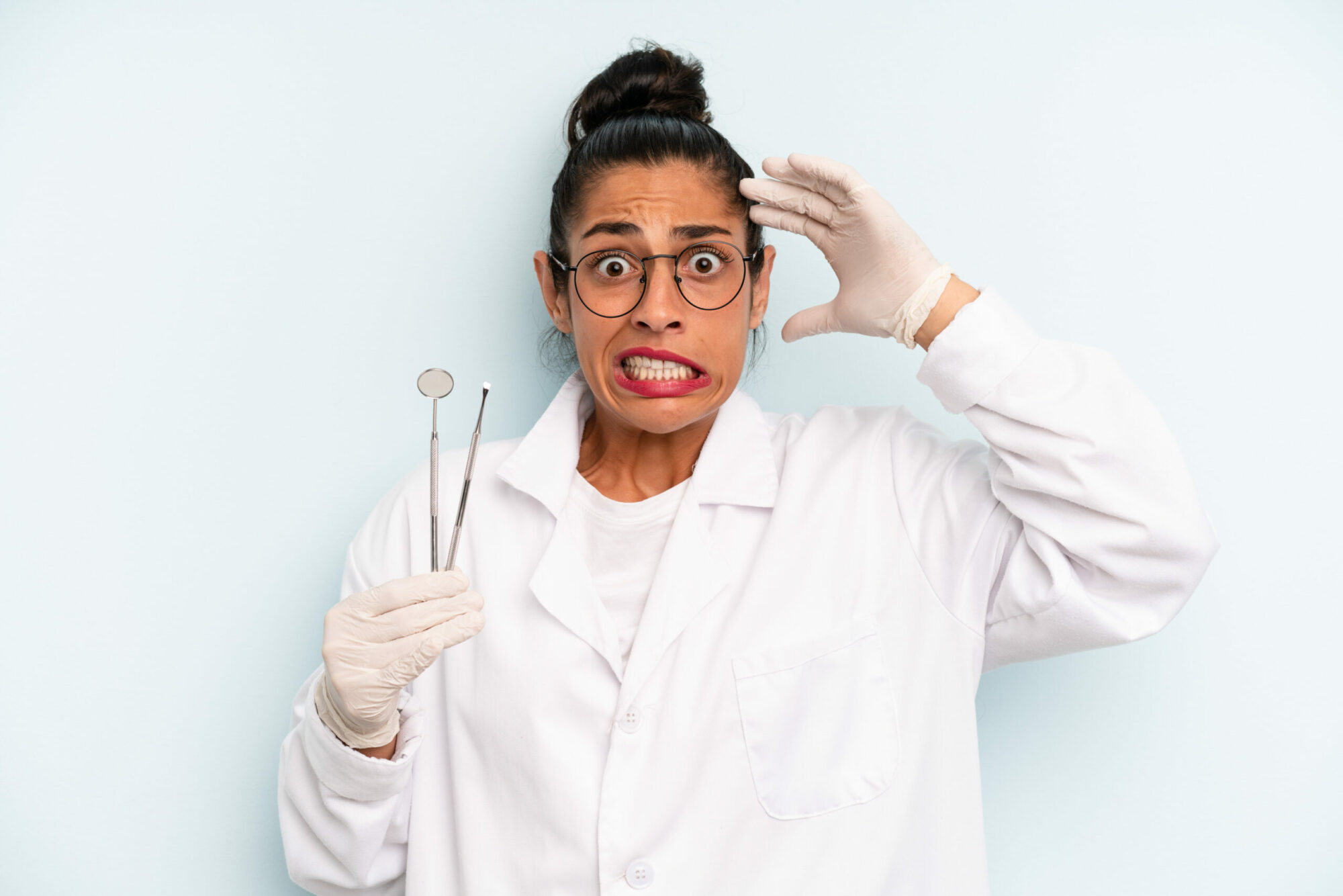 Hispanic woman feeling stressed, holding dental instruments.