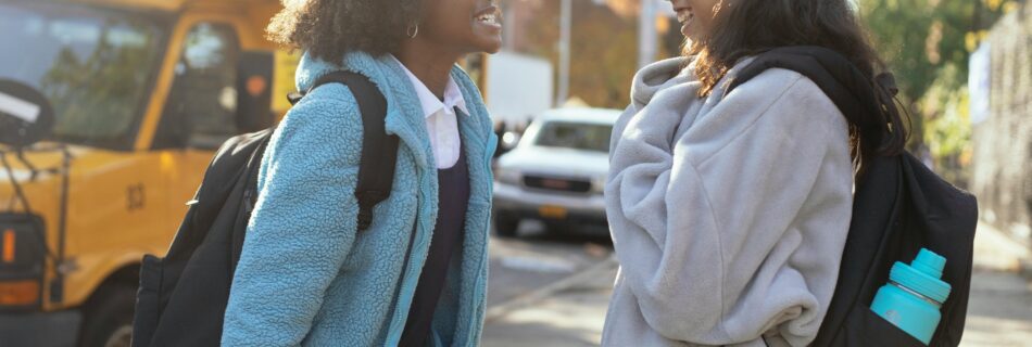 Two girls in front of a school bus showing off their smiles