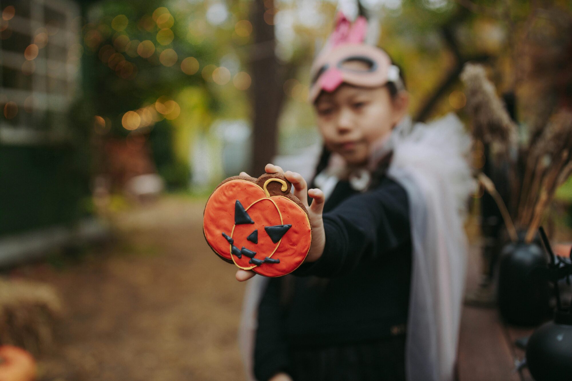 A kid n Halloween holding up a pumpkin cookie meant to discourage kids from eating too much sugar on halloween