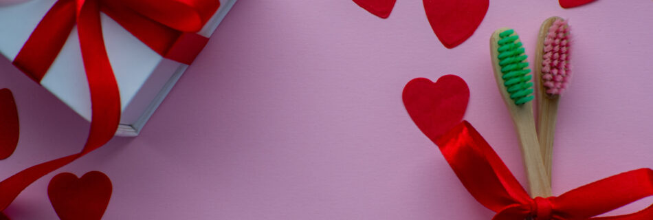 Hearts and tooth brushes over a pink background.