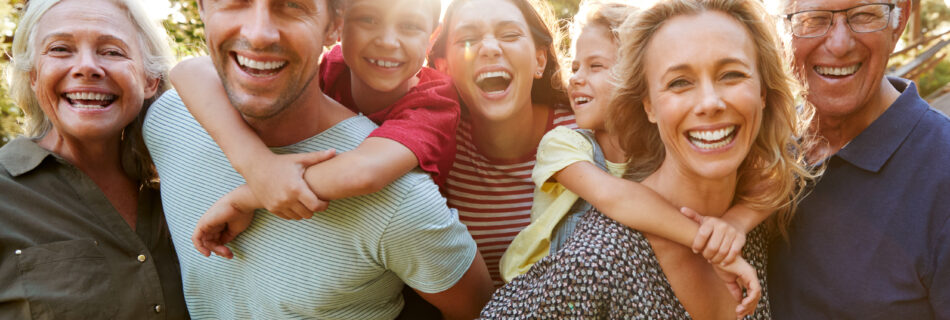 Outdoor Portrait Of Multi-Generation Family Smiling, Walking In Countryside Against Flaring Sun