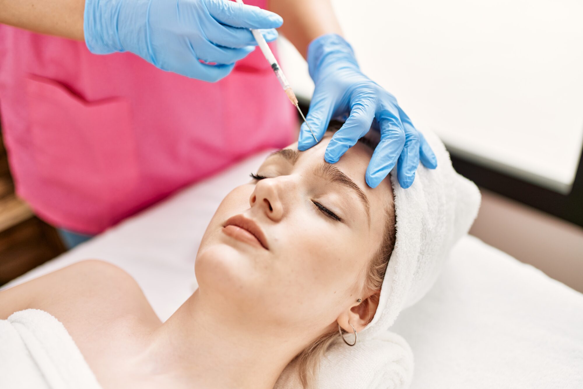 Doctor injecting botox on woman face for anti aging treatment at the clinic.